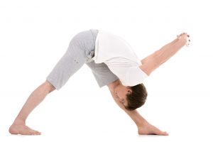 42500842 - sporty young man working out, yoga, pilates, fitness training, doing pyramid pose, intense side stretch posture, parsvottanasana, hands behind back, stretching exercise for shoulders and legs
